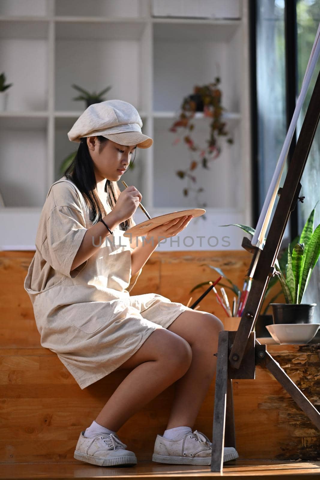 Young asian girl painting picture in art class.