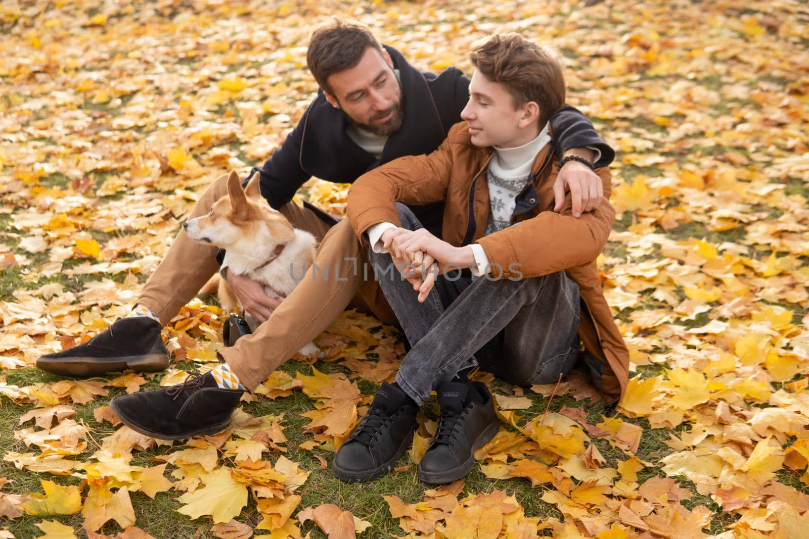 Father and son with a pet on a walk in the autumn park.