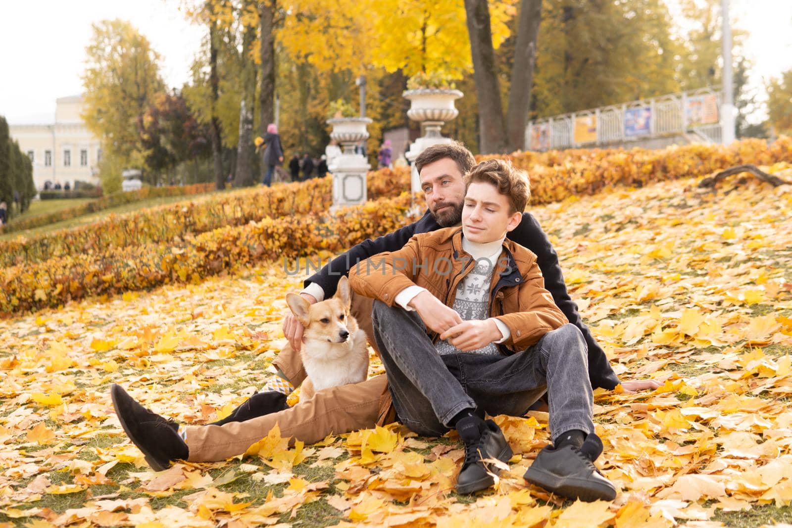 Father and son with a pet on a walk in the autumn park.