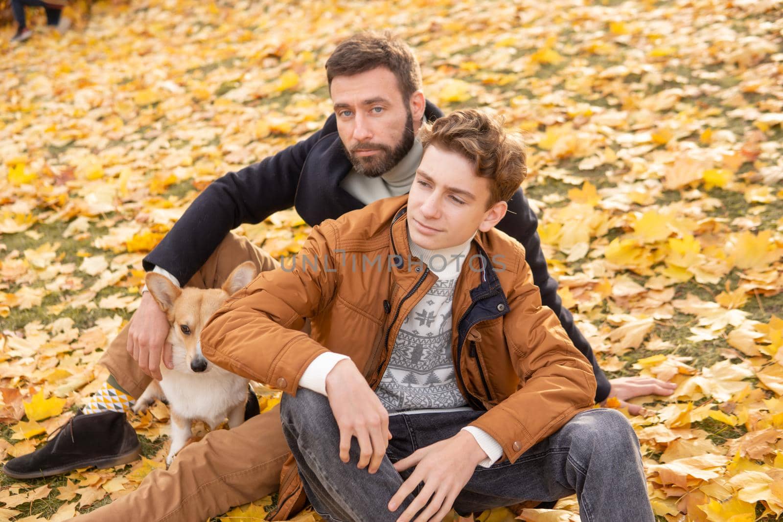 Father and son with a pet on a walk in the autumn park.