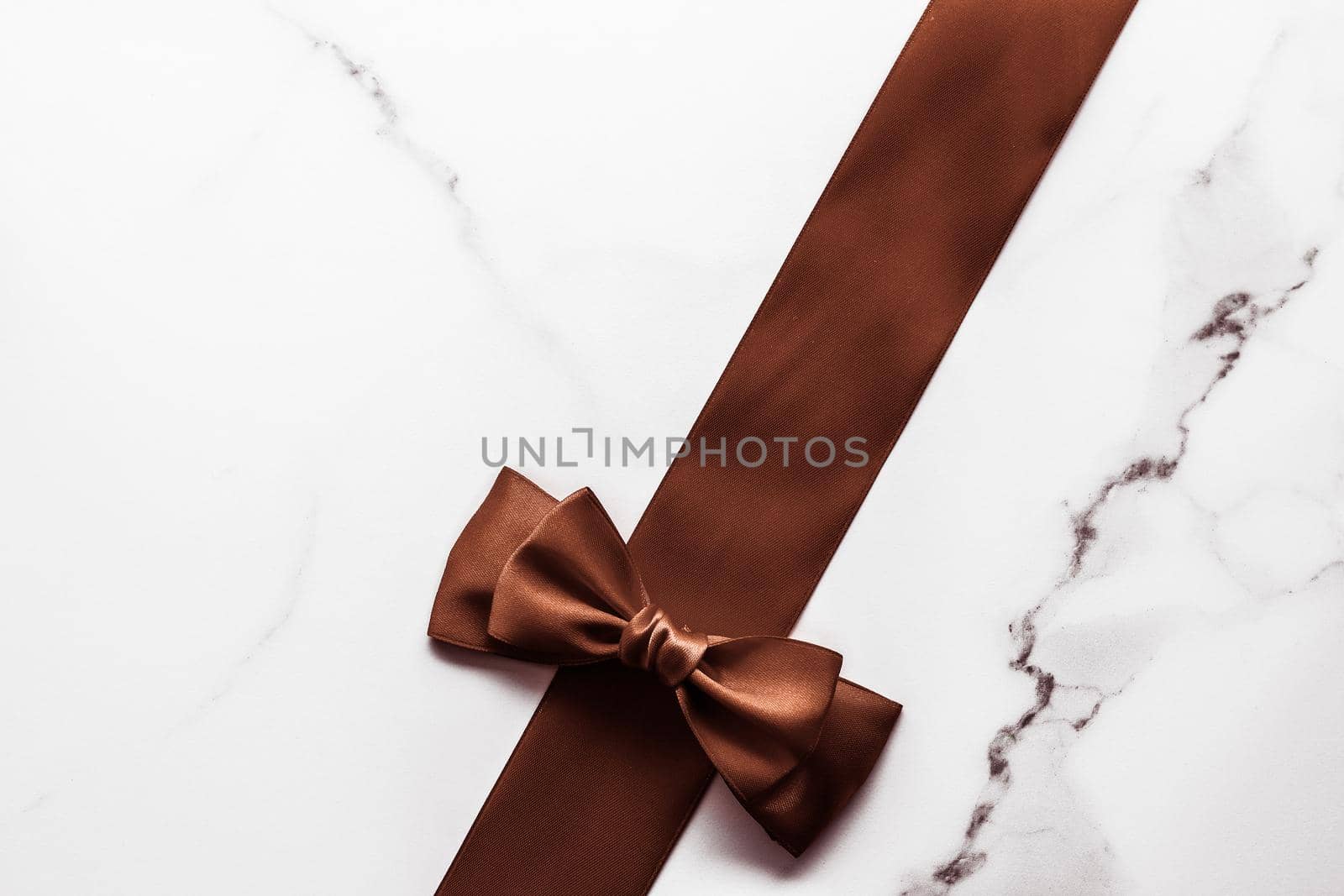 Holiday gift, decoration and sale promotion concept - Chocolate brown silk ribbon on marble background, flatlay