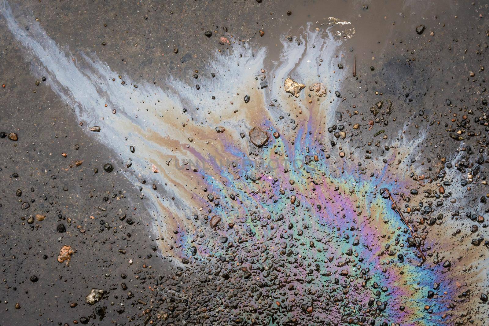 Oil stain on the asphalt, rainbow-shaped colored gasoline stains on an asphalt road as a texture or background