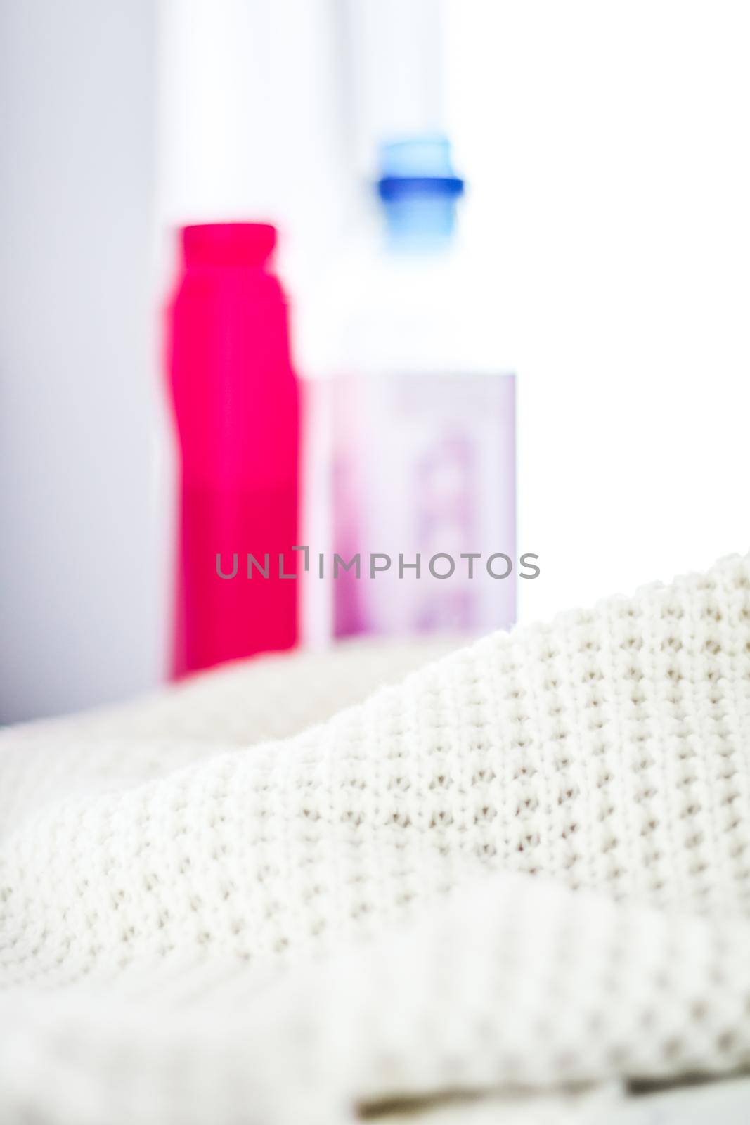 Housekeeping, fabric textures and handmade knitwear concept - Warm knitted clothes and liquid laundry detergent
