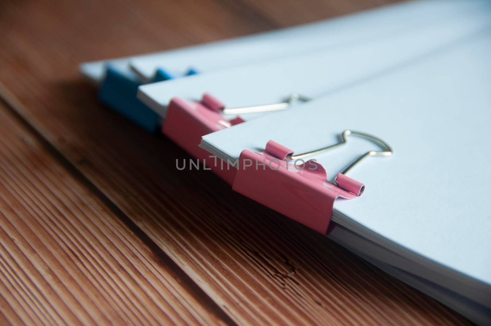 Paper stack of clipped pile of documents on wooden desk. Copy space and business offices concept.