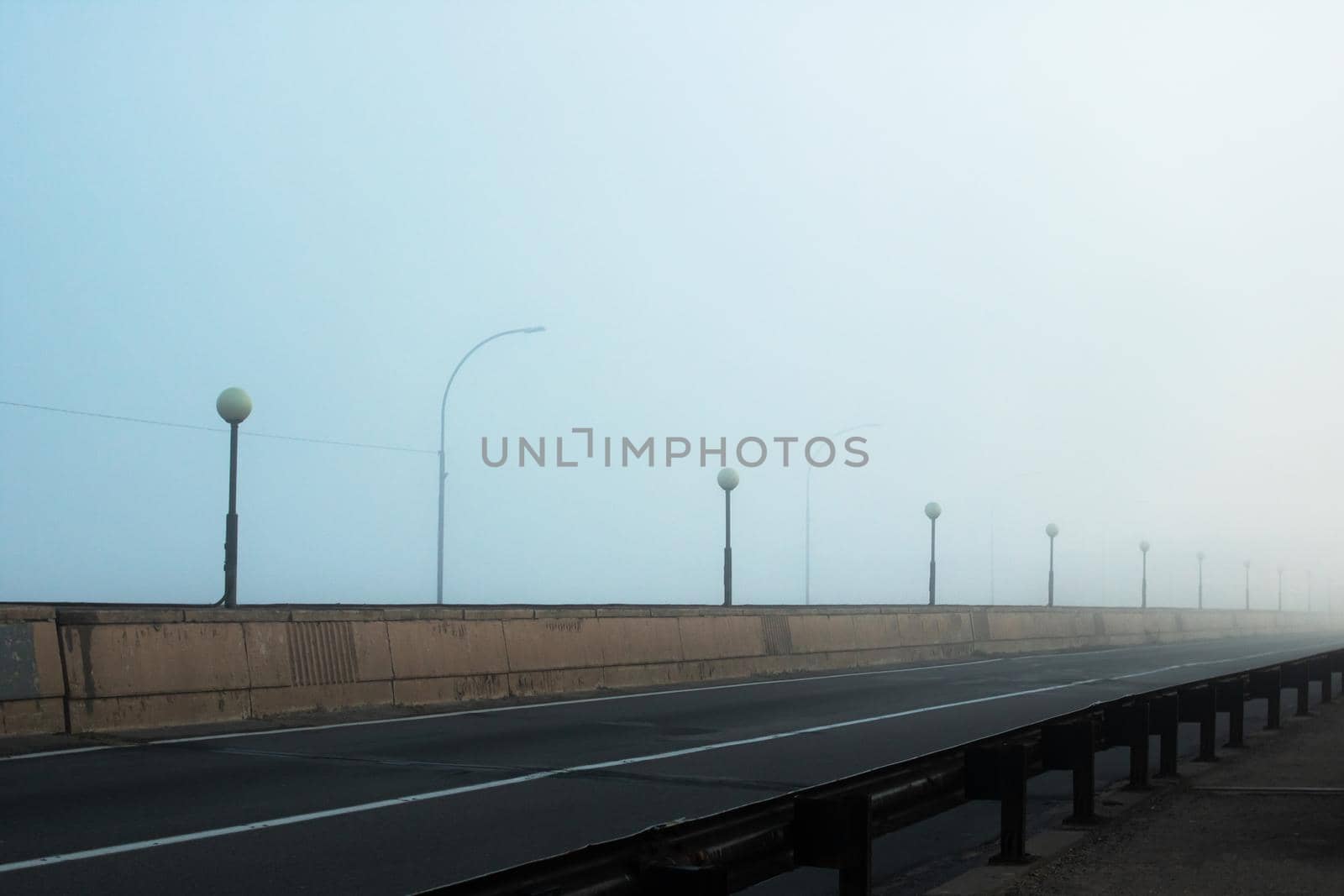 Bridge and road in the fog at dawn close up