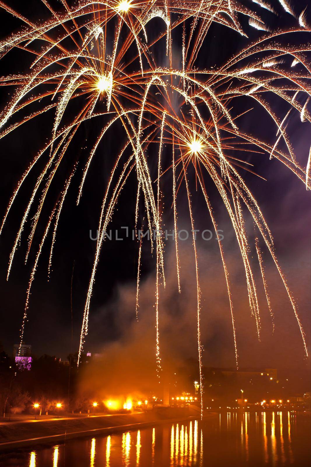 Flash of fireworks in night sky over river in city. Holiday concept by Laguna781