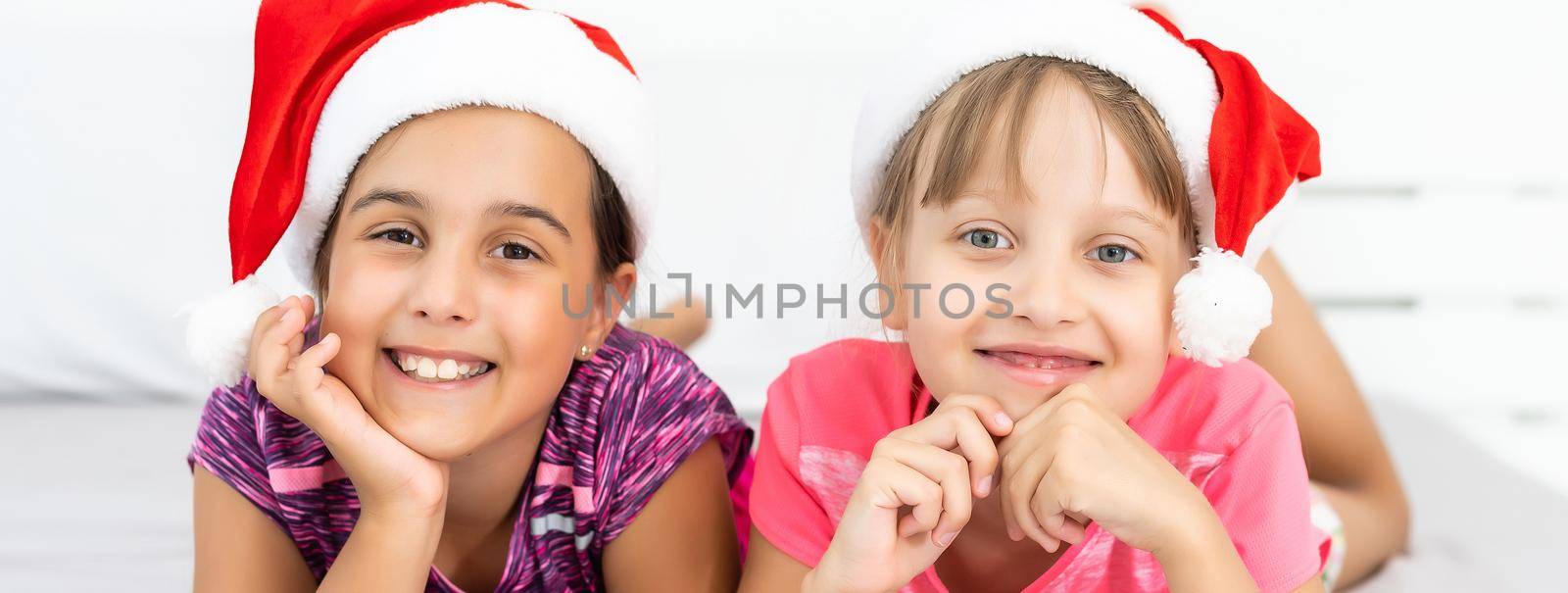 two little girls friends or sisters with hats and playing and cuddling and laughing at winter time.