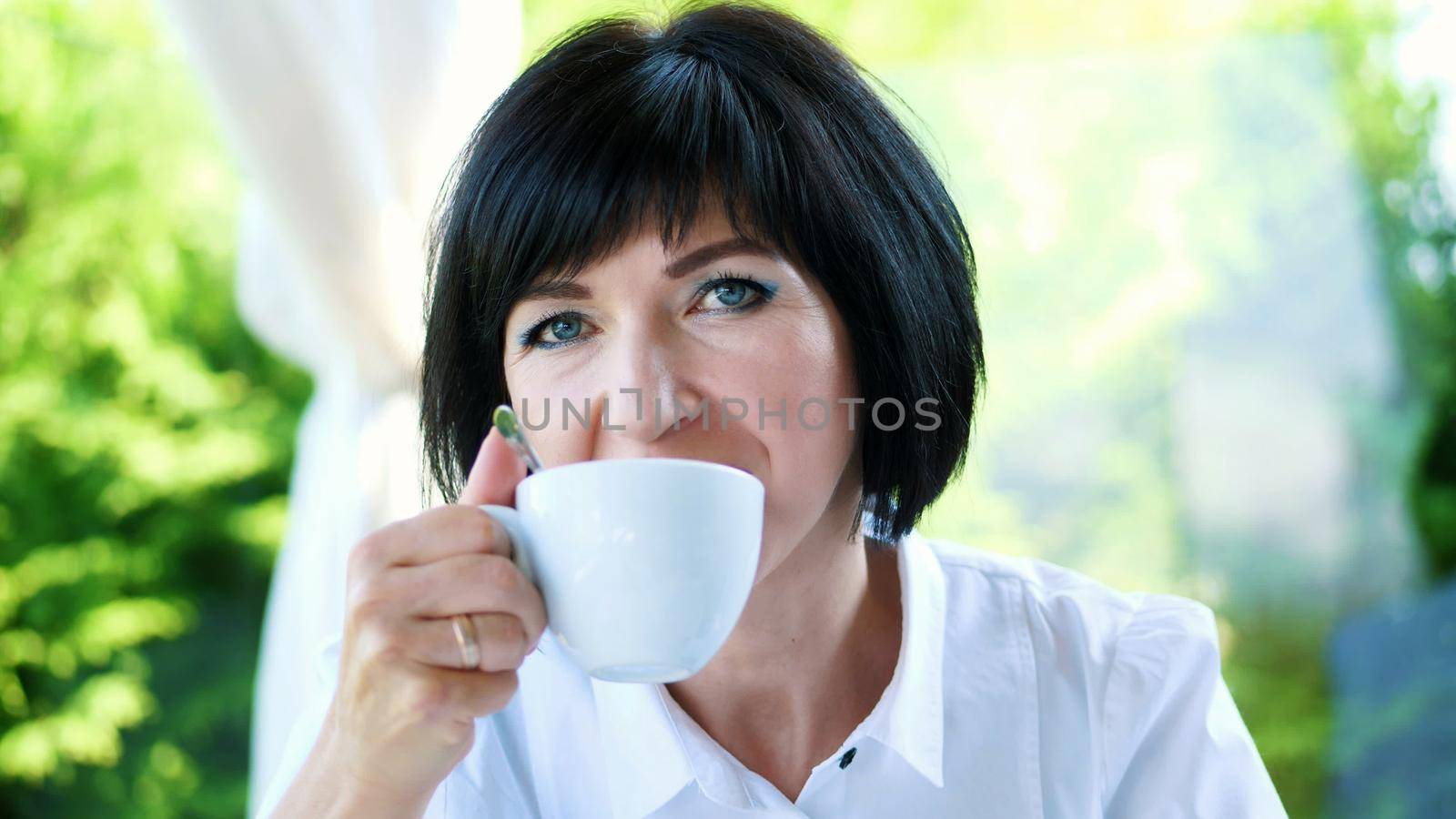 Portrait of pleasant smiling, Happy beautiful real 40 years old Ukrainian woman. a woman drinks tea without taking out a teaspoon. High quality photo