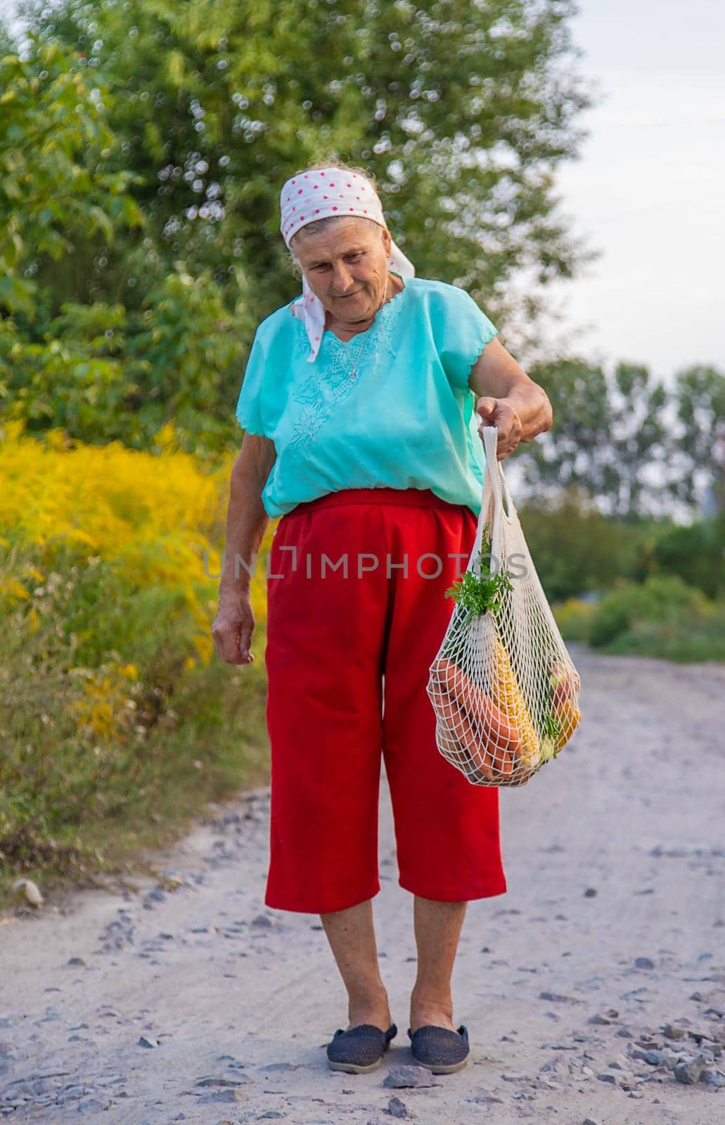 Grandmother carries vegetables in a shopping bag. Selective focus. by yanadjana