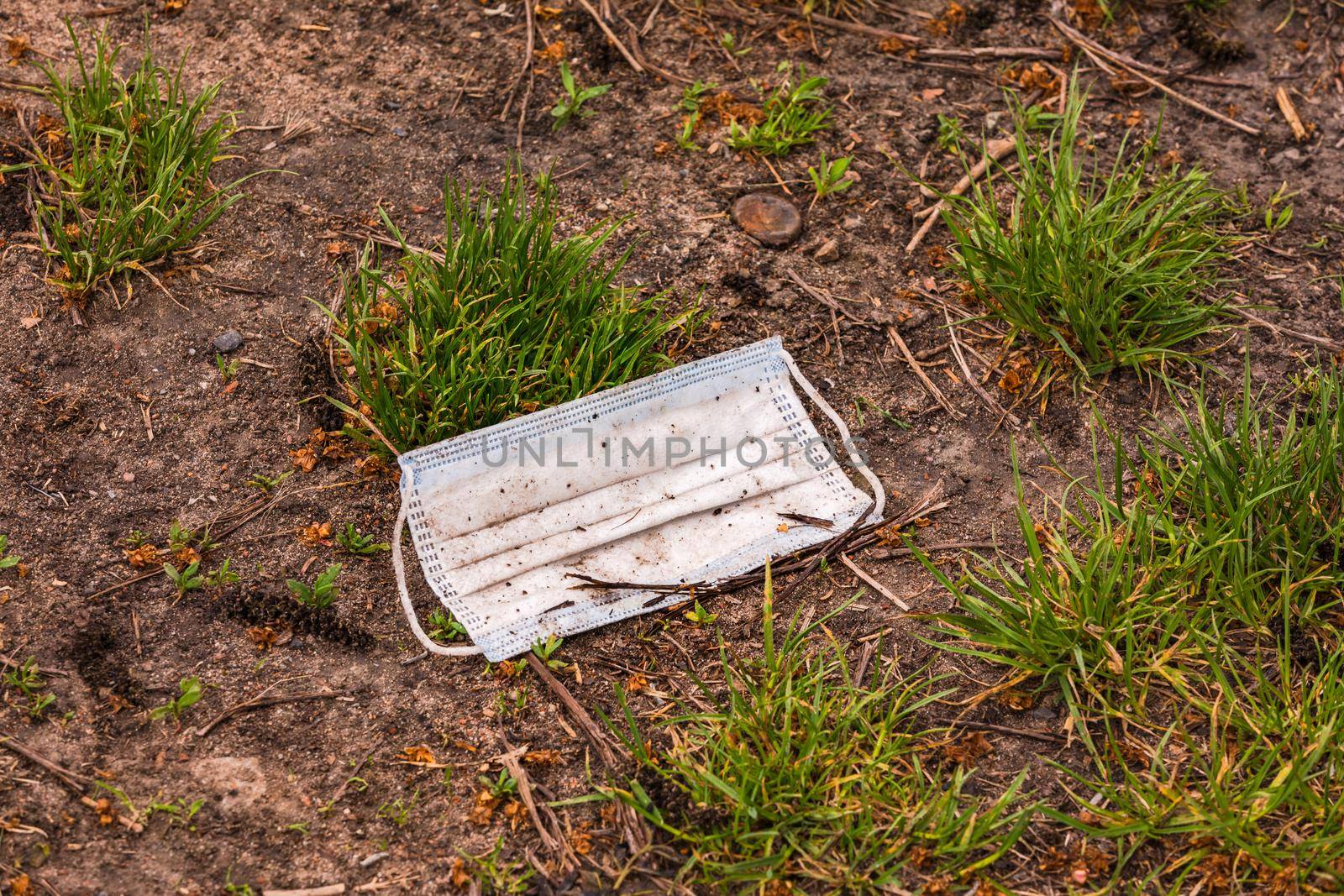 A surgical mask lost in the COVID-19 pandemic pollutes the environment in a field