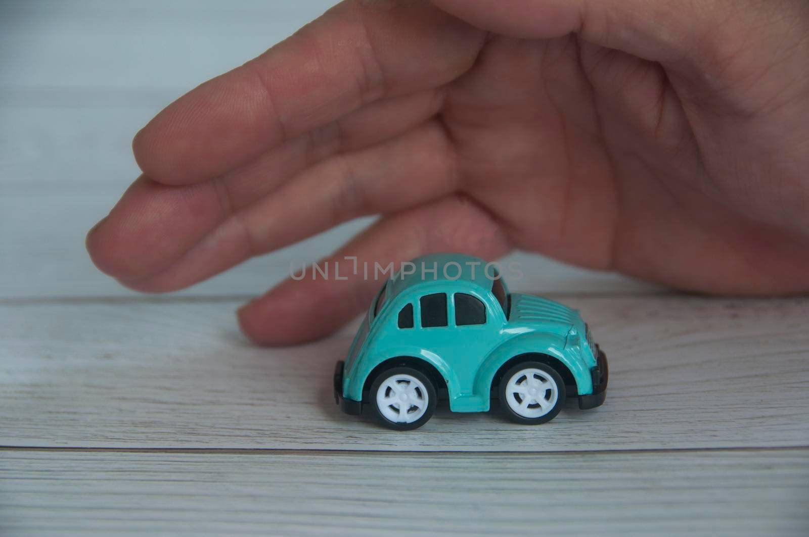 Hand covering toy car - Insurance and security concept.