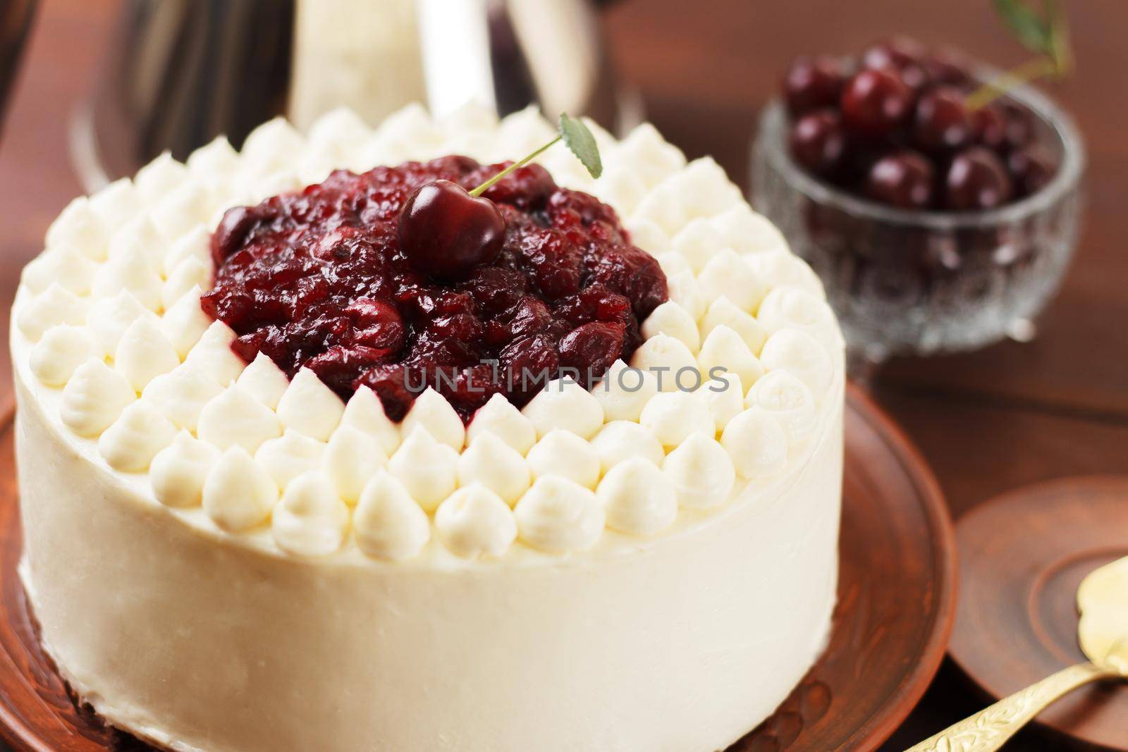 Biscuit cake, cherry souffle with cream cheese and cherry confiture on wooden background. Close-up