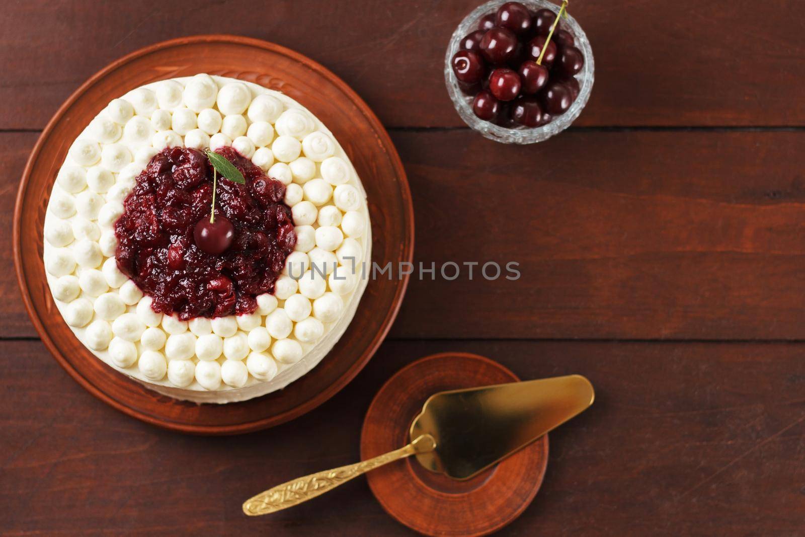 Biscuit cake, cherry souffle with cream cheese and cherry confiture on wooden background copy space
