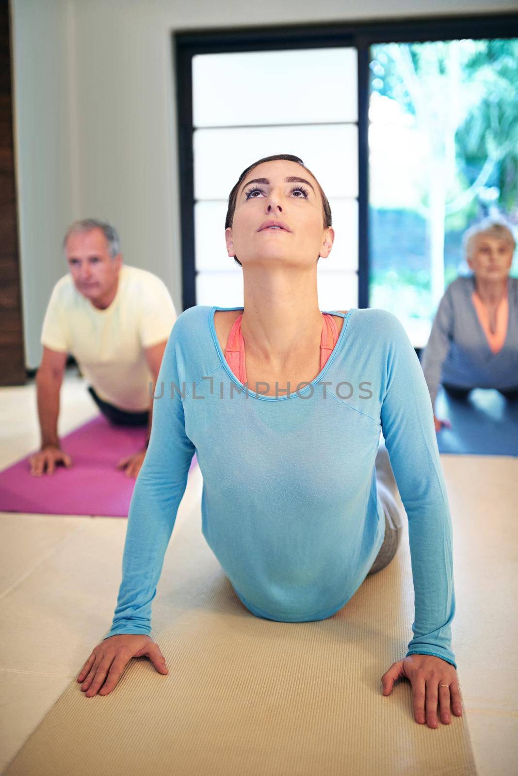 The healthier you are, the better you feel. a yoga instructor guiding a senior couple in a yoga class. by YuriArcurs