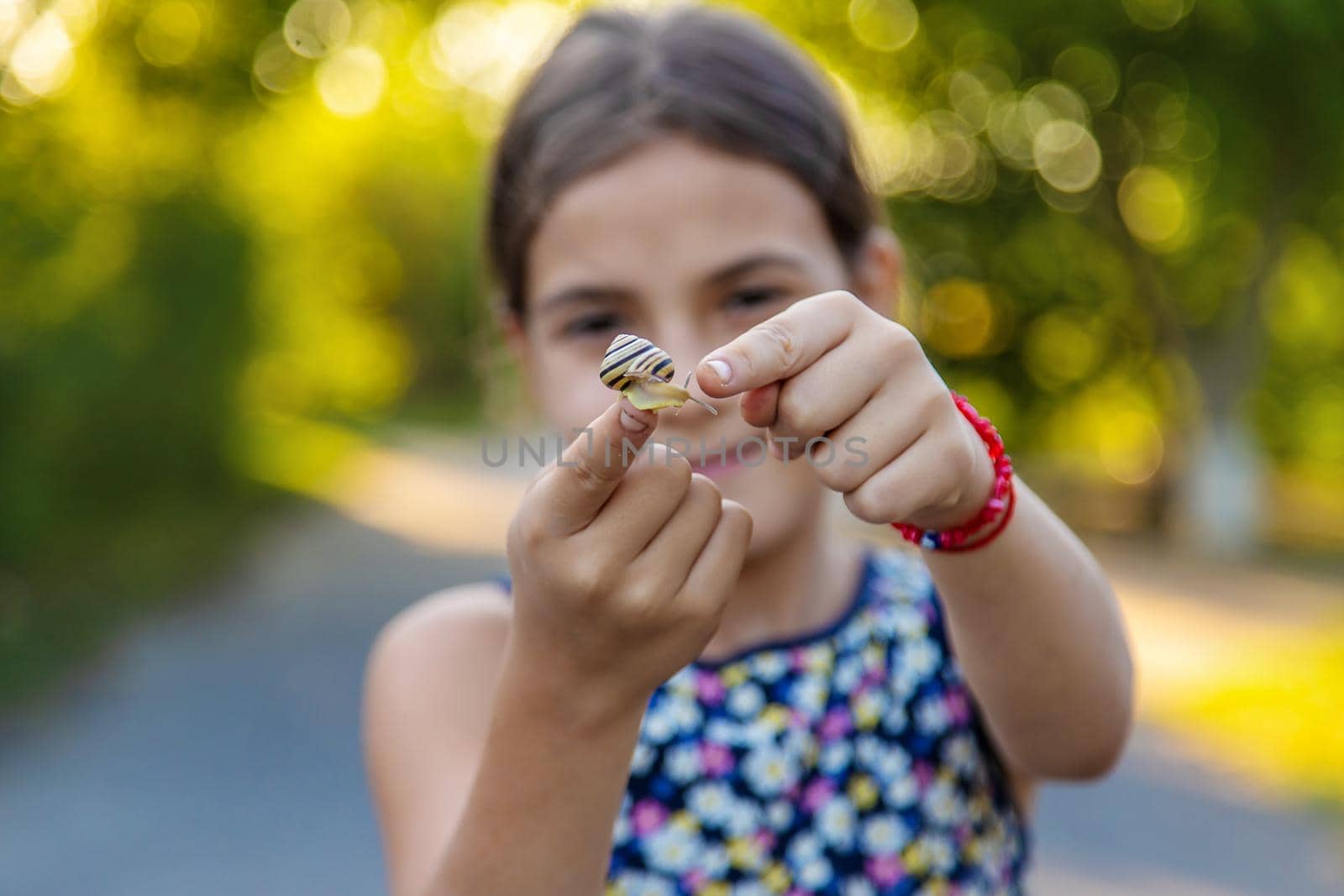 A child is studying a snail in the park. Selective focus. Nature.