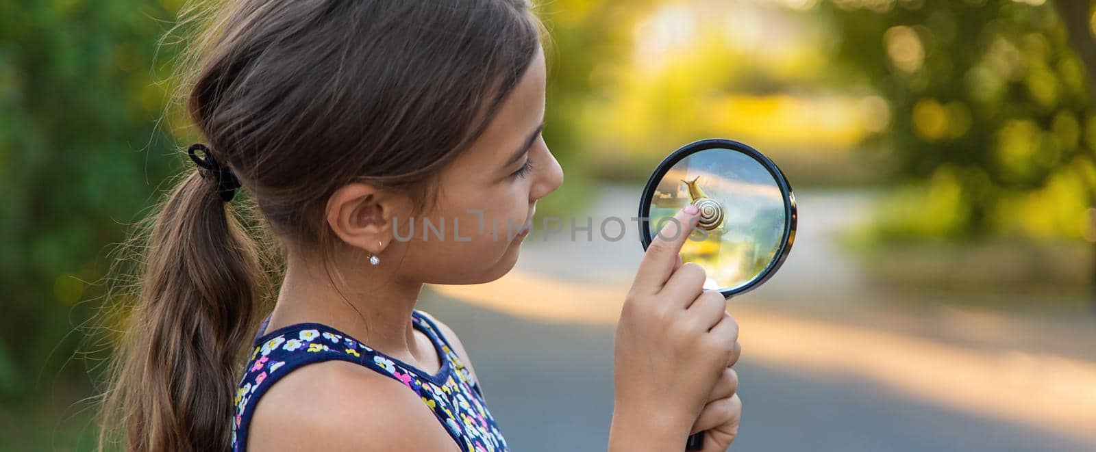 A child is studying a snail in the park. Selective focus. Nature.