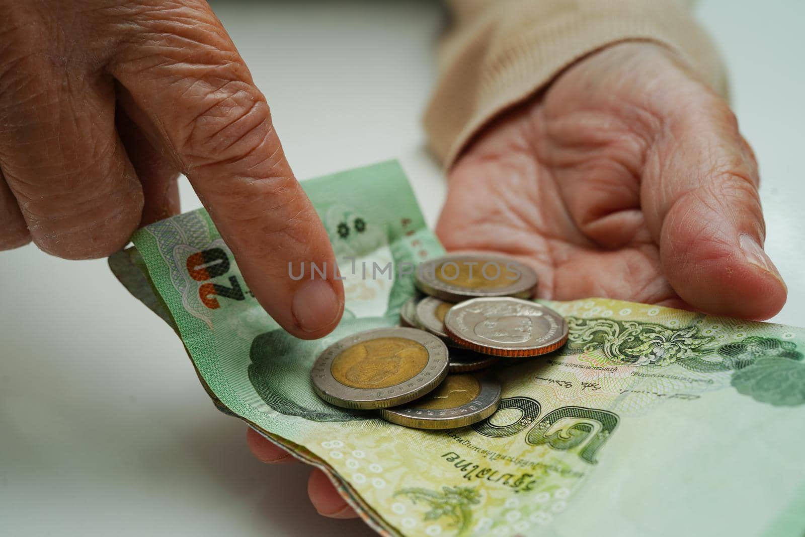 Retired elderly woman counting coins money and worry about monthly expenses and treatment fee payment.