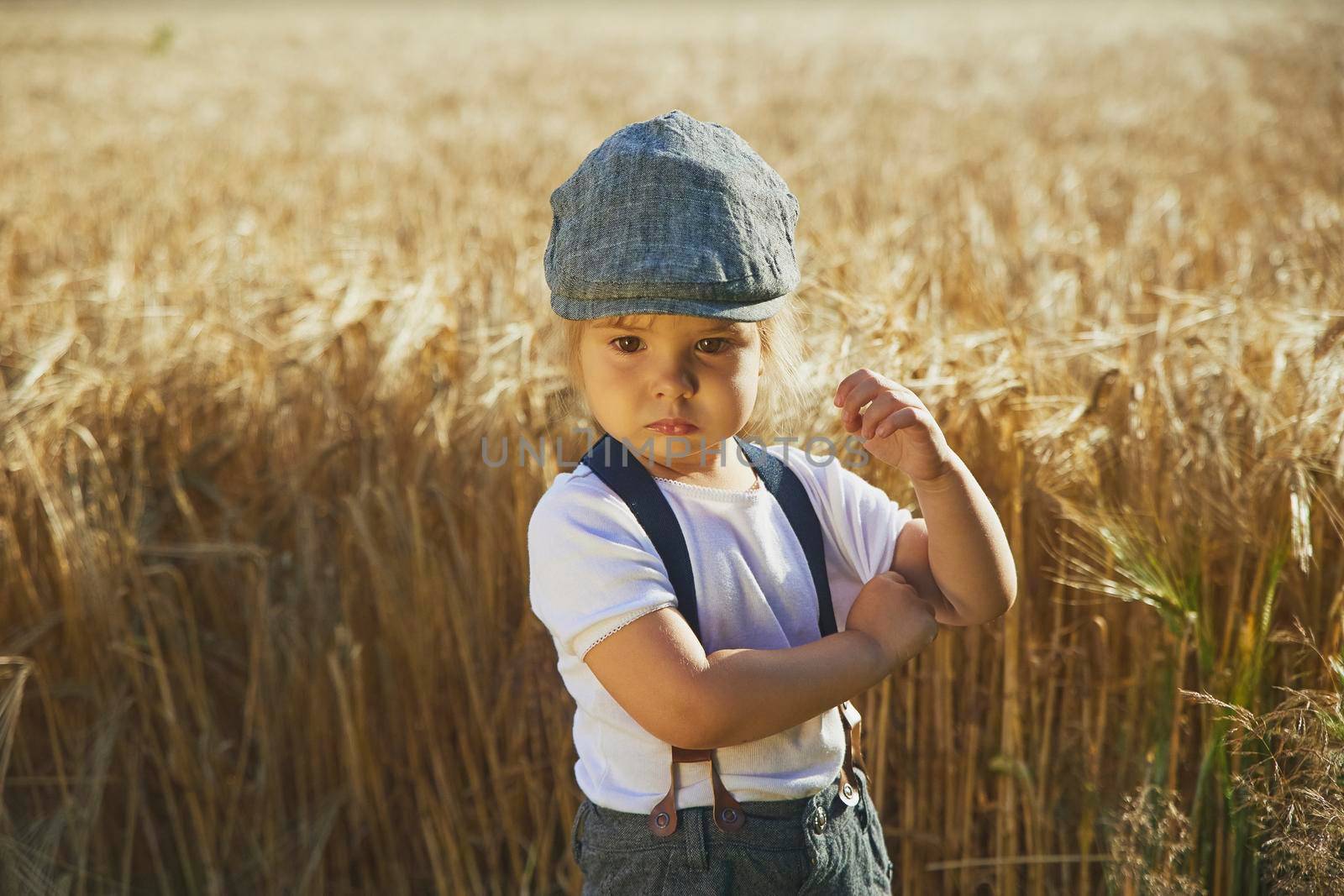 Adorable sad street child in a field at sunset.