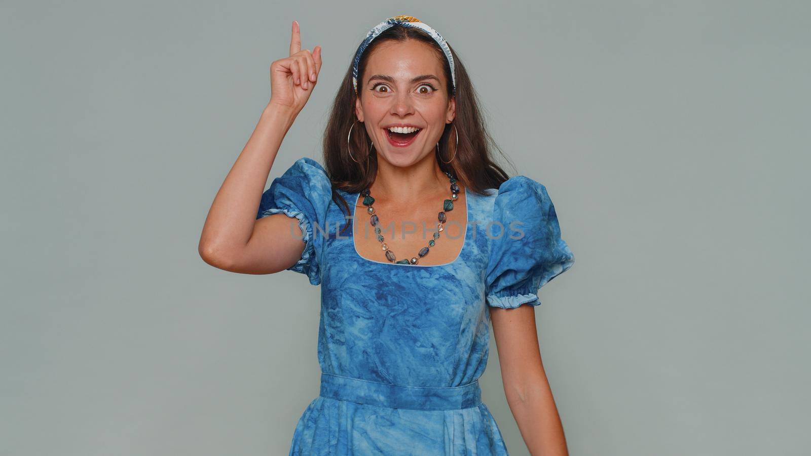 Eureka. Inspired woman pointing finger up with open mouth, having good idea, plan, startup, showing inspiration motivation gesture, problem solution. Adult stylish girl on gray studio background
