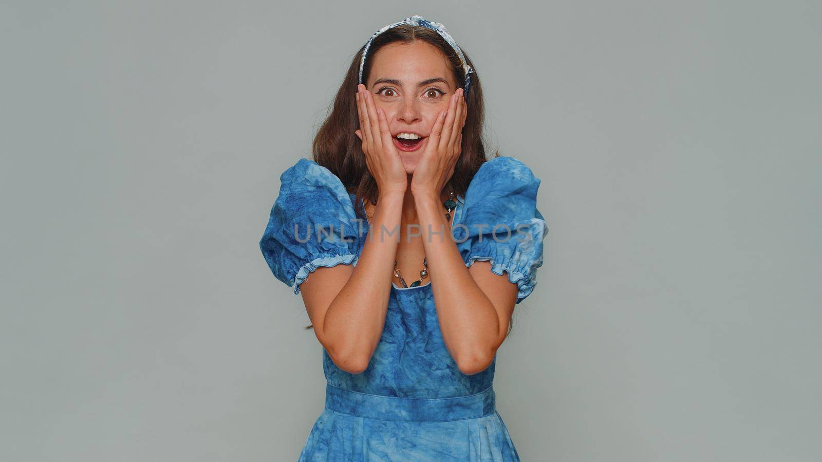 Oh my God, Wow. Excited amazed woman looking surprised at camera with big eyes, shocked by sudden victory game winning, lottery goal achievemen, good news. Adult girl on gray studio background indoor