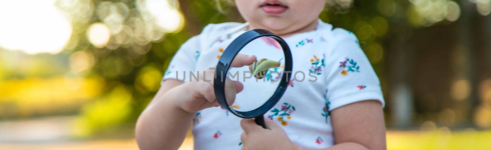 A child is studying a snail in the park. Selective focus. by yanadjana