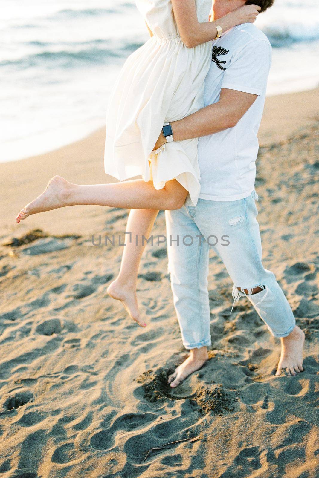 Man holding a woman in his arms on the beach. Cropped. High quality photo