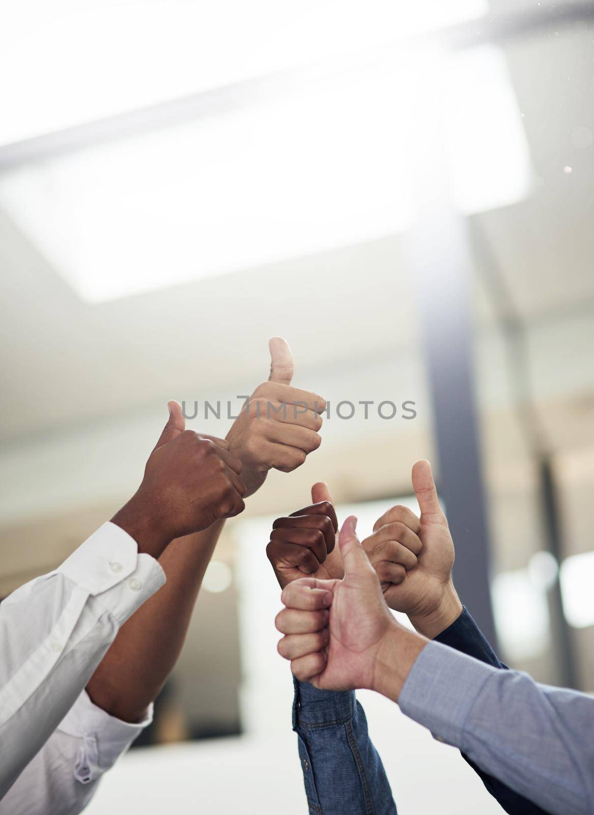 Were all in agreement here. a group of unidentifiable businesspeople showing thumbs up in the office. by YuriArcurs