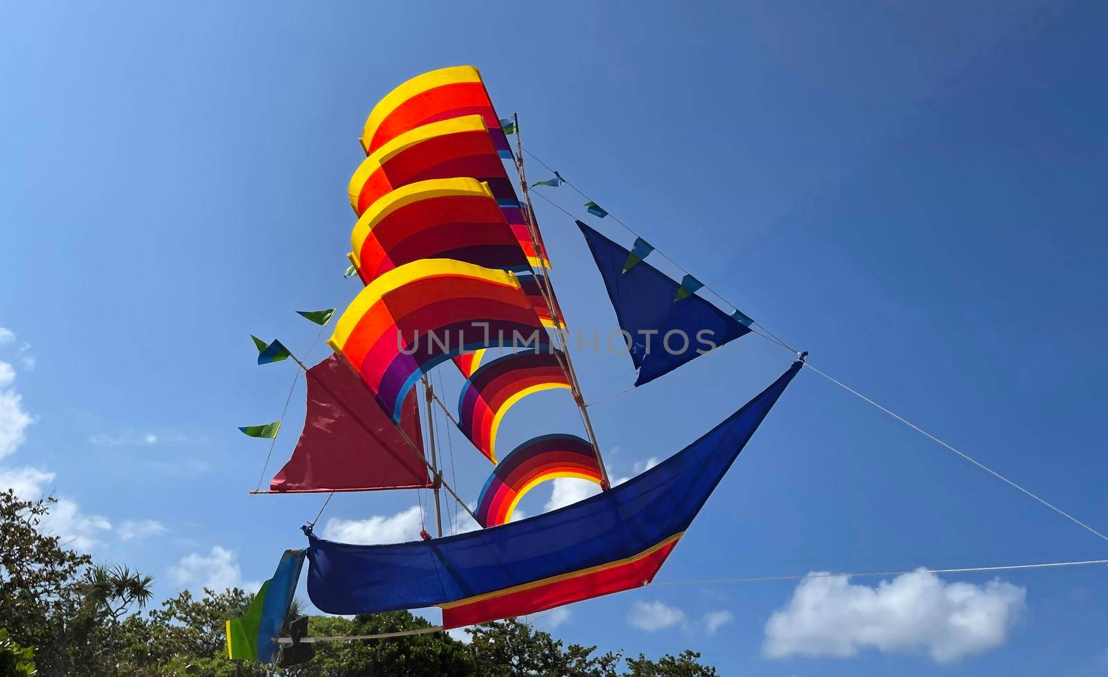 flying ship, rainbow colored ship kite flies on the blue sky and cloud in the beach