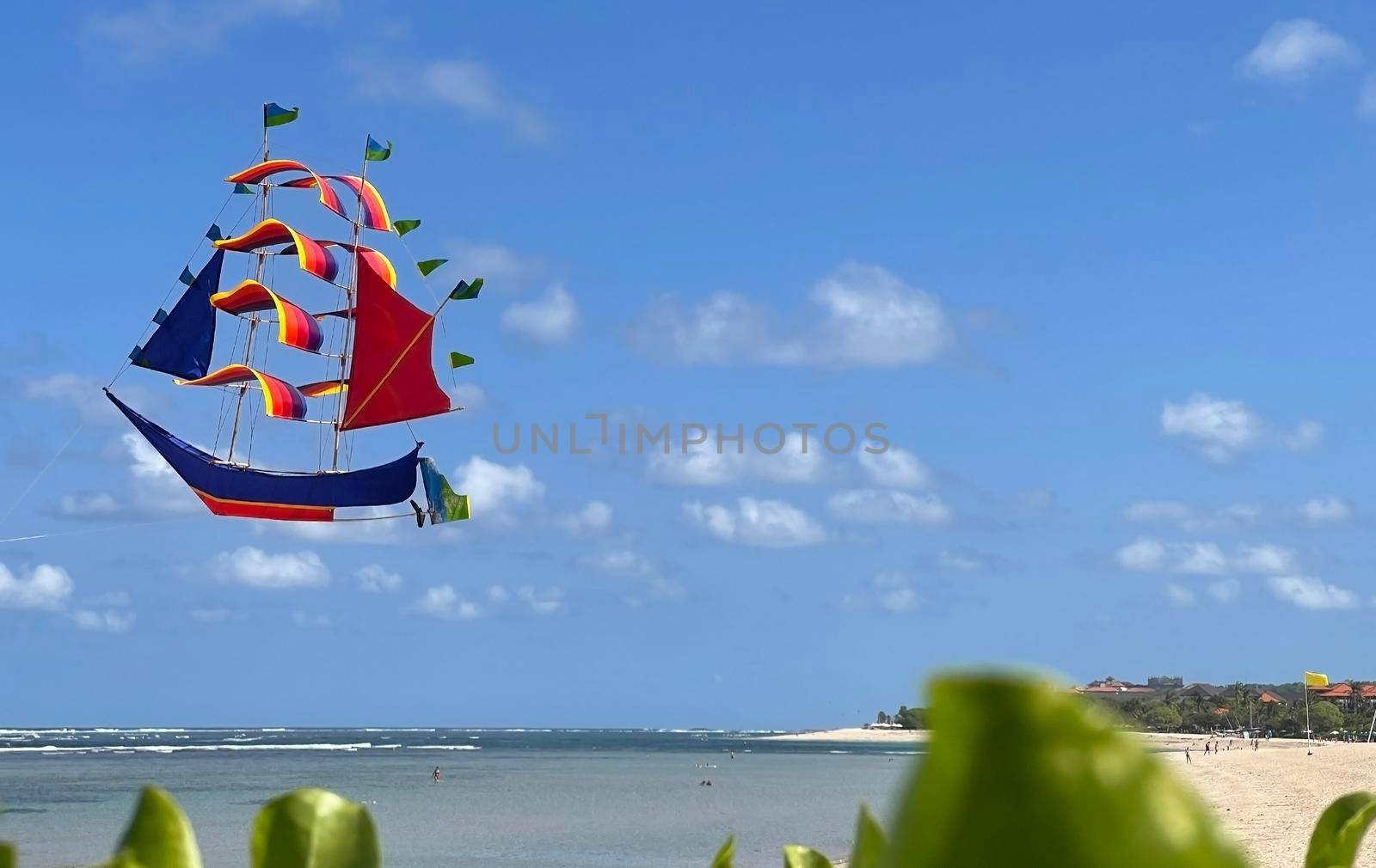 flying ship, rainbow colored ship kite flies on the blue sky and cloud in the beach