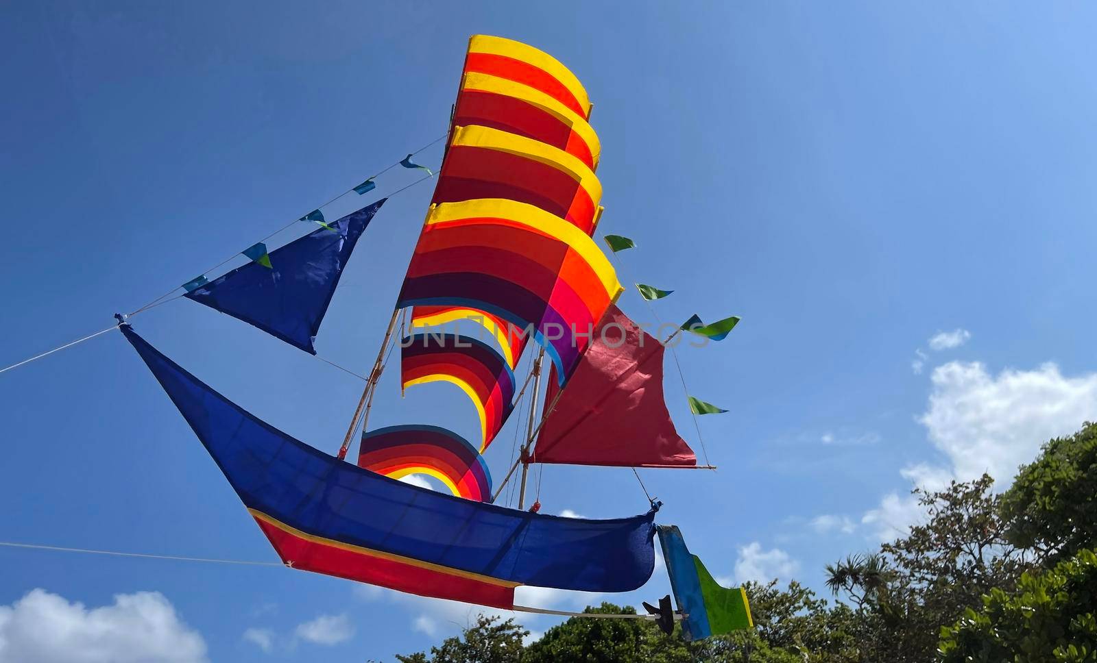 flying ship, rainbow colored ship kite flies on the blue sky and cloud in the beach