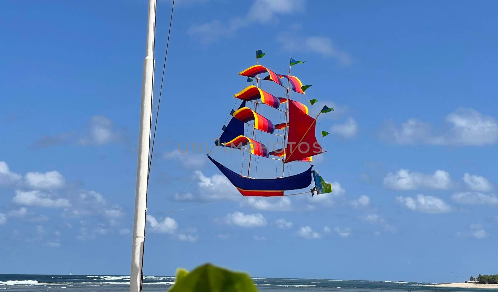 flying ship, rainbow colored ship kite flies on the blue sky and cloud in the beach