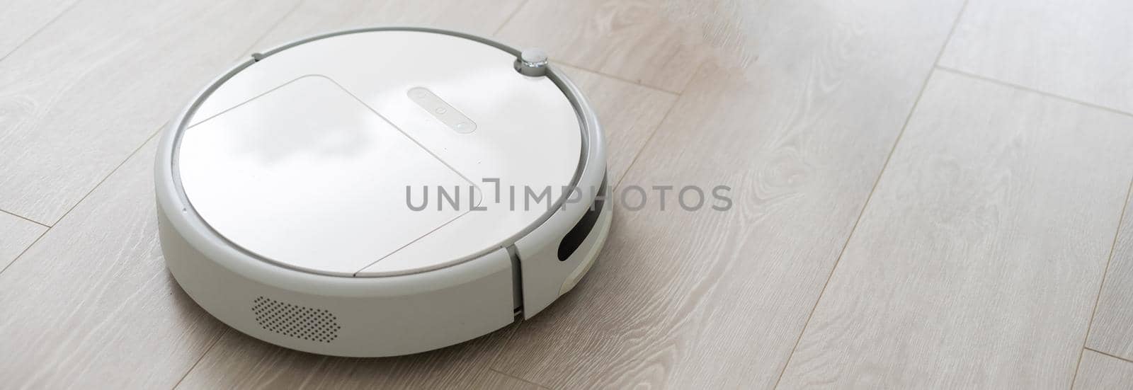 Woman using robotic vacuum cleaner at home.Female legs near robot cleaner. by Andelov13