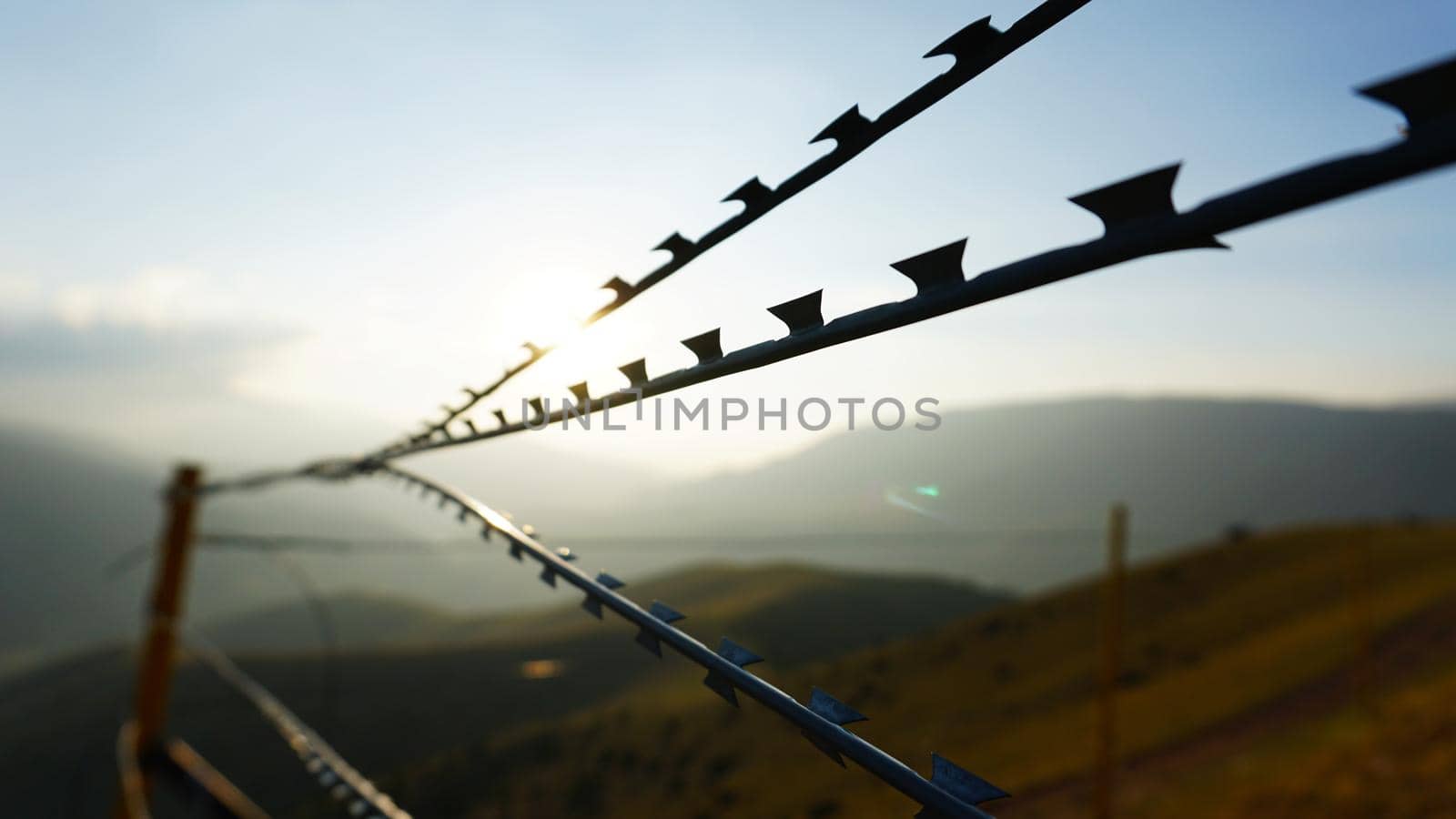 Sharp barbed wire on fence with blurry background by Passcal
