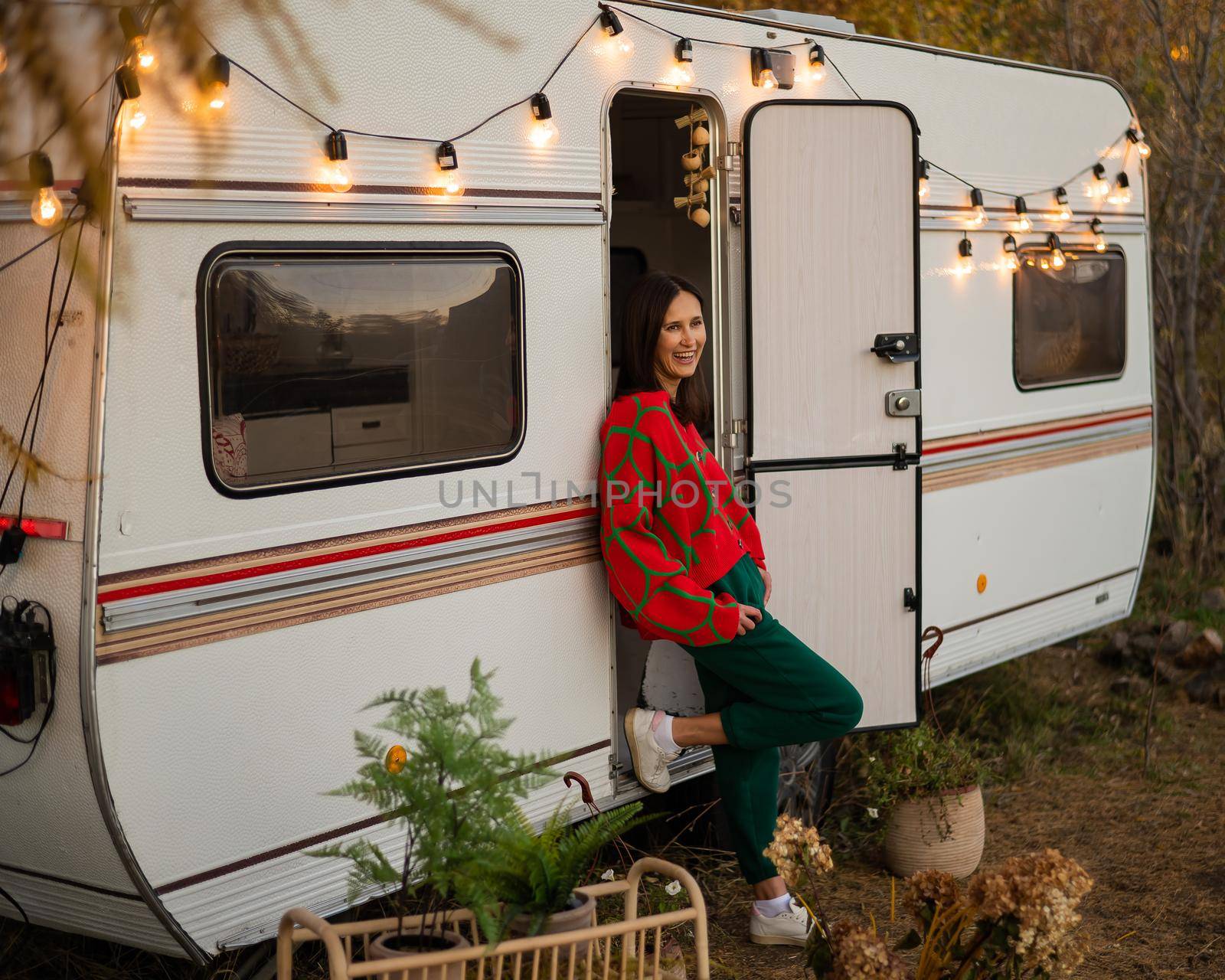 Caucasian woman in oversized red knitted jumper travels in motorhome in autumn