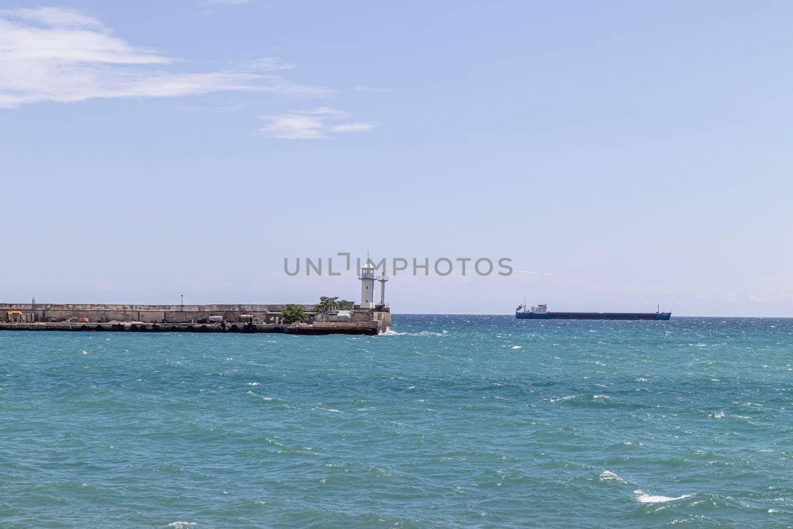 lighthouse on the pier and cargo ship. photo