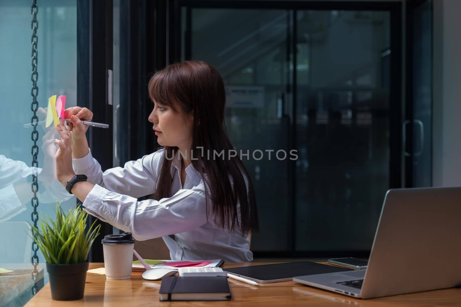 Asian Business woman taking note on sticky note.