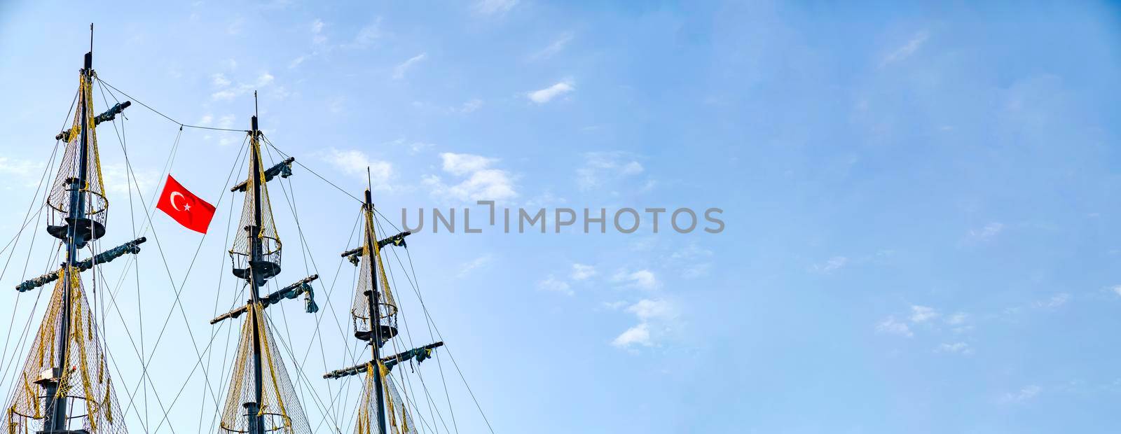 The masts of the ship with the Turkish flag on the background of the blue sky. The concept of travel and freedom