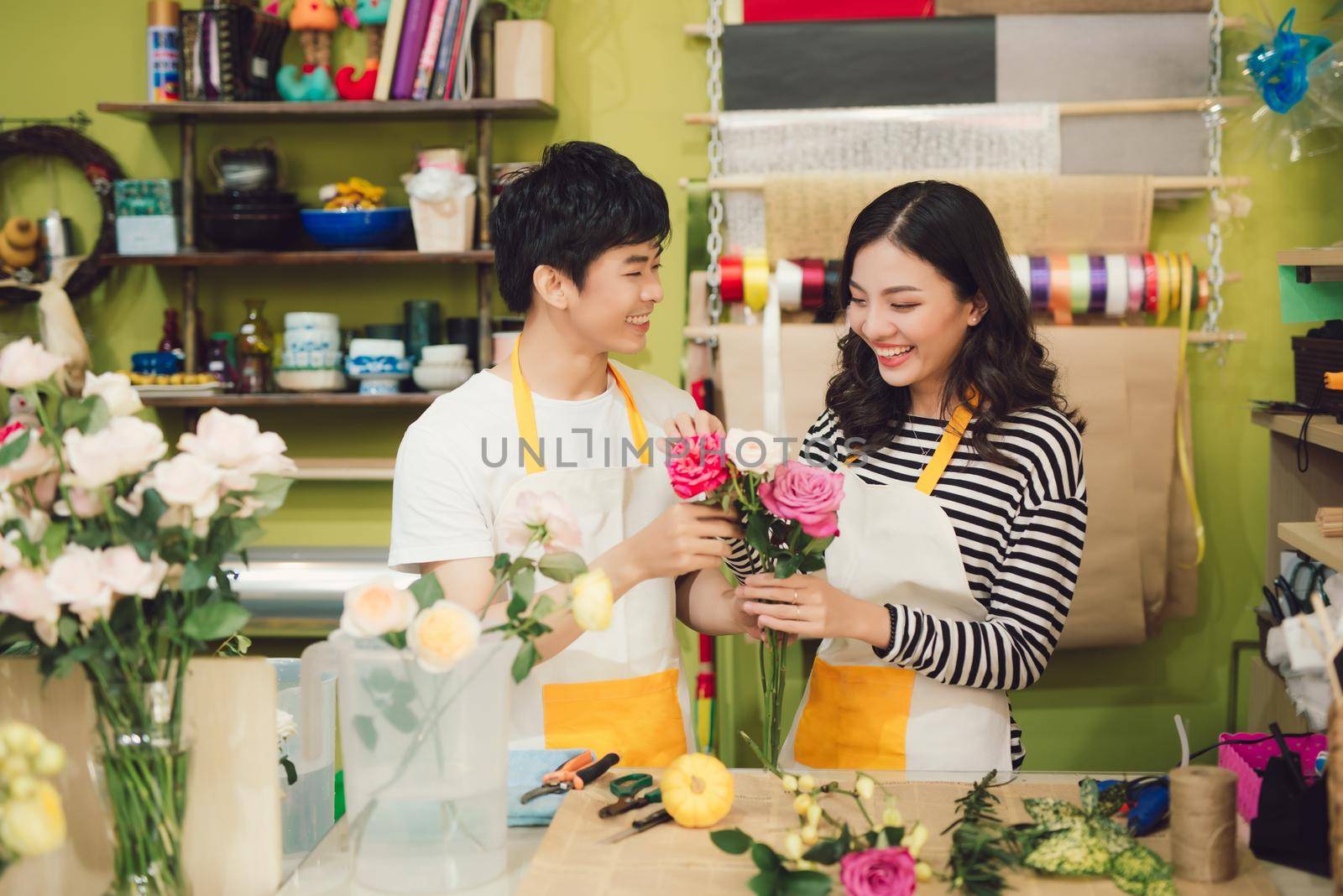 Florists making bouquet at table against wooden background by makidotvn