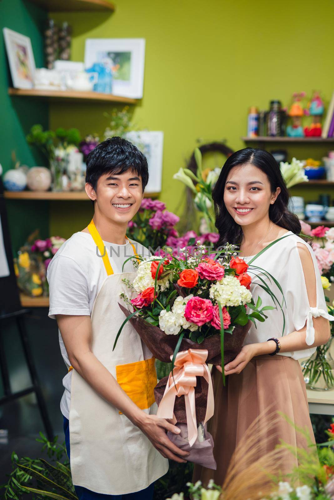 Male florist offering flowers at the counter in the florist shop by makidotvn