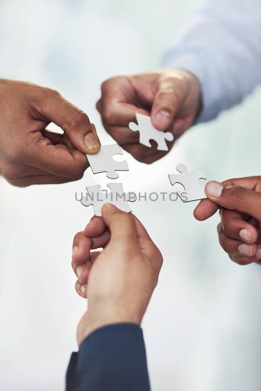 The pieces of their plan are falling into place. High angle shot of a group of unidentifiable businesspeople holding puzzle pieces together. by YuriArcurs