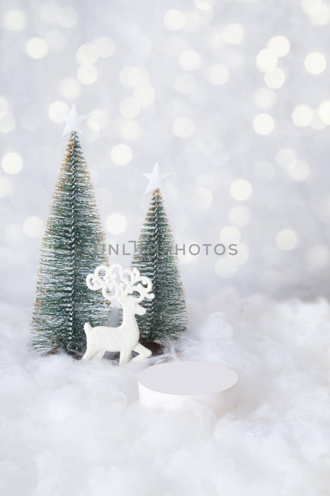 Podium or pedestal mok-up for cosmetics in the snow with a christmas tree on a bokeh background vertical format