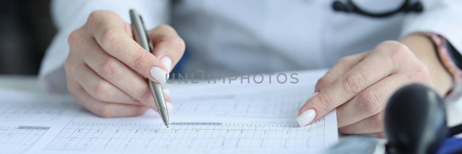 Doctor cardiologist examining patient cardiogram on paper in clinic closeup. Ecg diagnostics of rhythm and conduction disorders concept