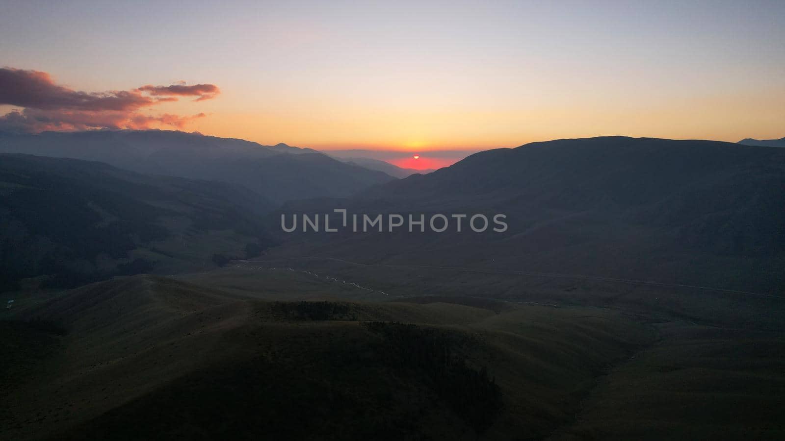 Red rays of the sun at sunset among the mountains by Passcal