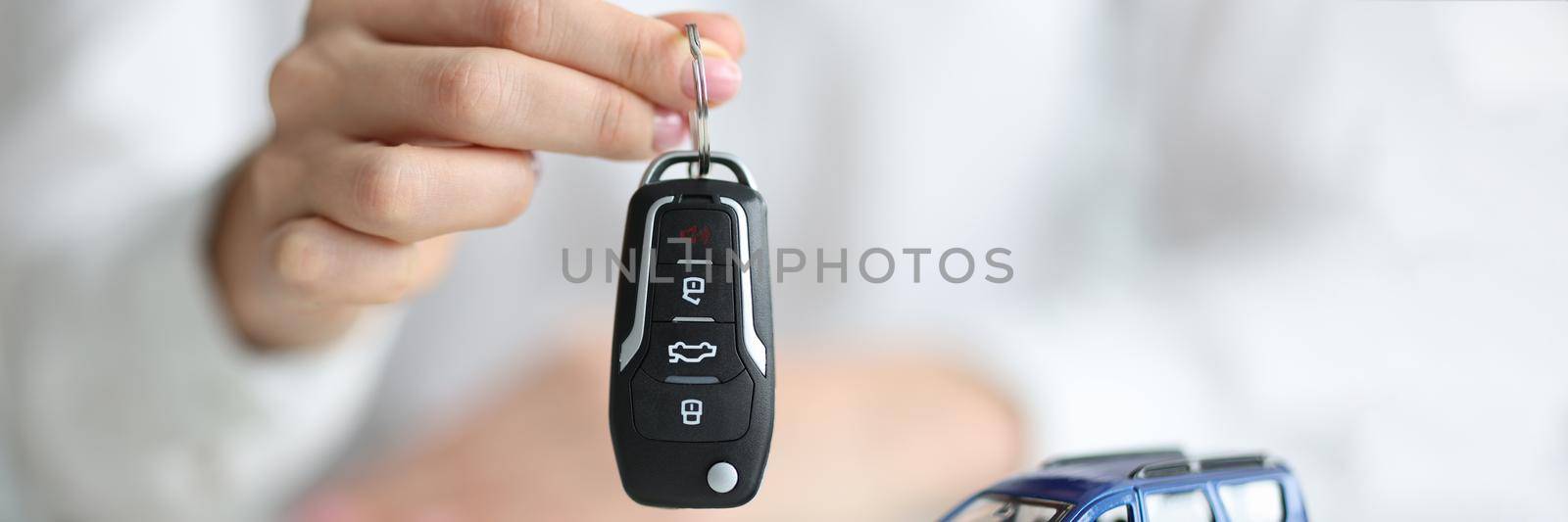 Dealer holding keys in front of toy car and money closeup. Sale and rental of cars concept