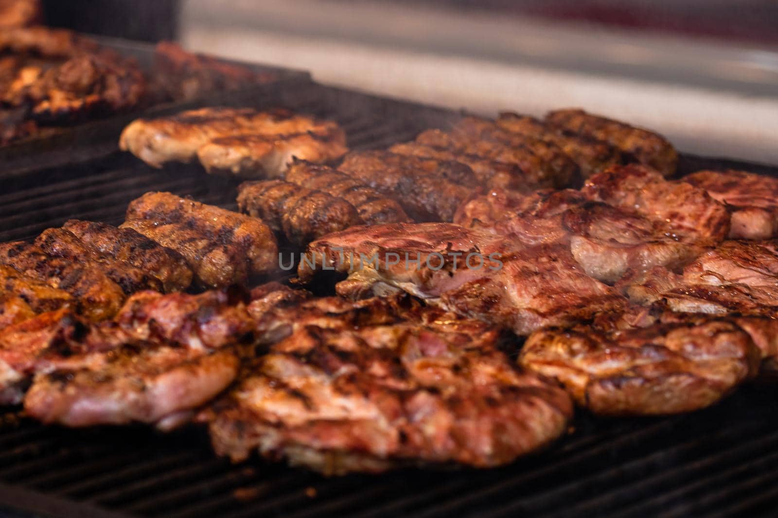 Grilling tasty food on barbecue. Steak, sausages on grill at food festival by vladispas