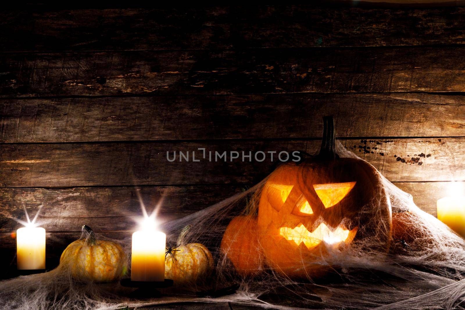 Festive mystical halloween interior. Pumpkin, spider web, burning candles, spiders on dark wooden background