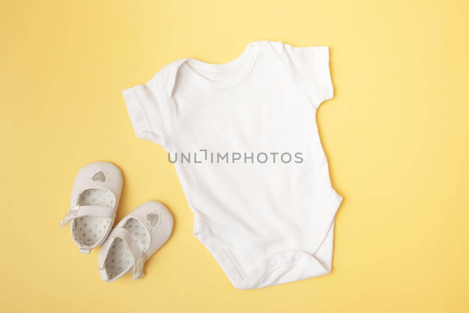 Baby clobodysuit mock-up top view with pumpkins on yellow background for your text or logo place