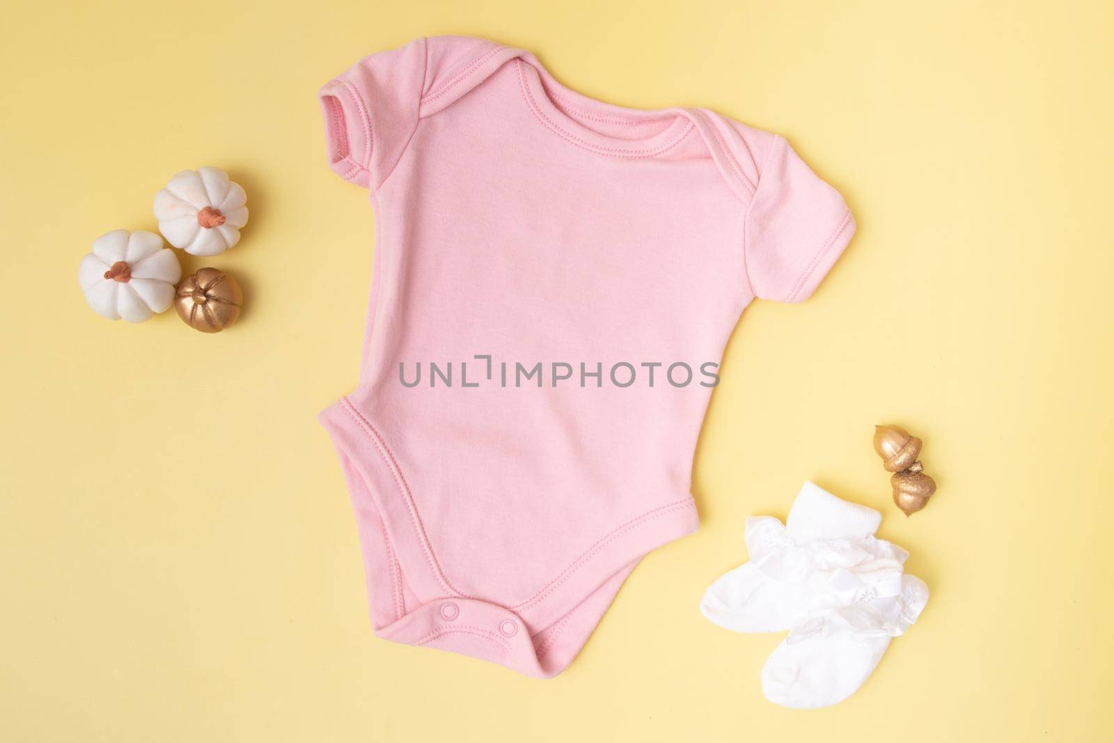 Baby clobodysuit mock-up top view with pumpkins on yellow background for your text or logo place in autumn season