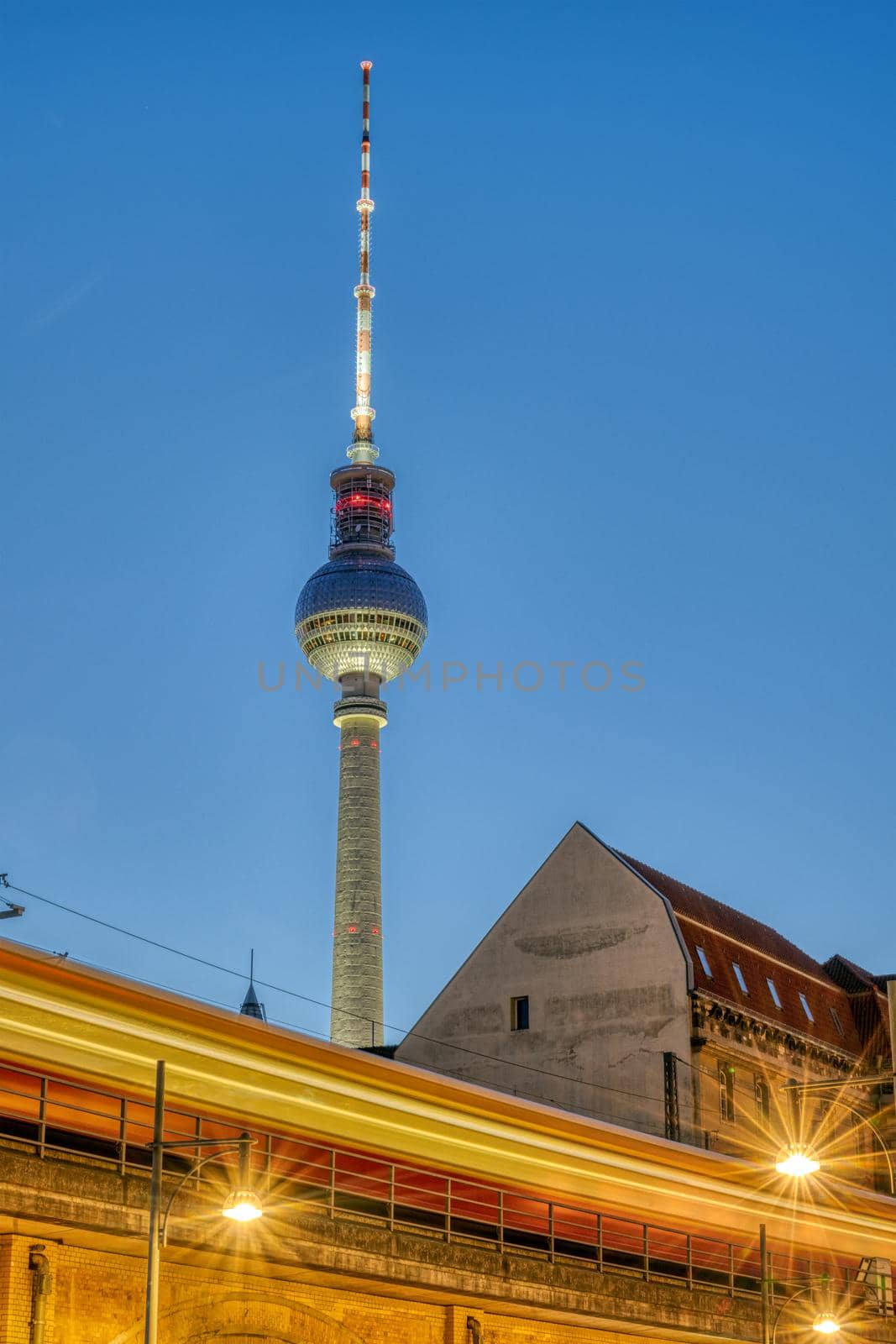 The famous TV Tower in Berlin at twilight with a motion blurred commuter train