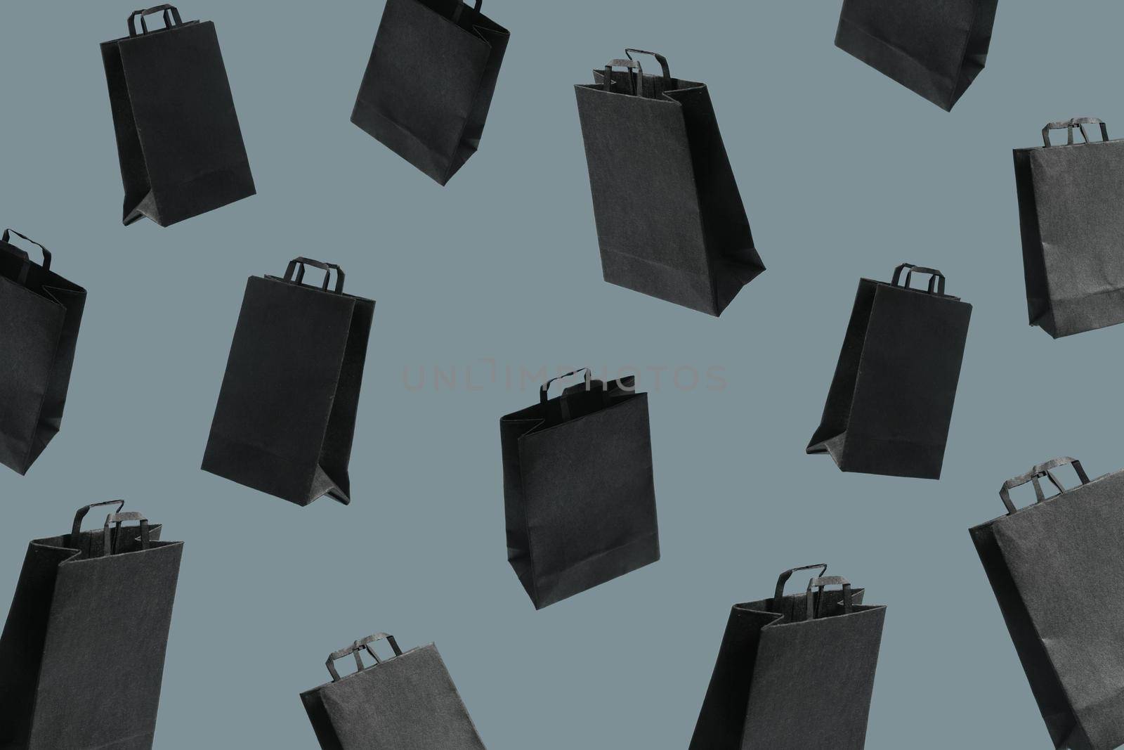 Pattern from black sale shopping bags are flying on yellow background. Black Friday creative idea concept